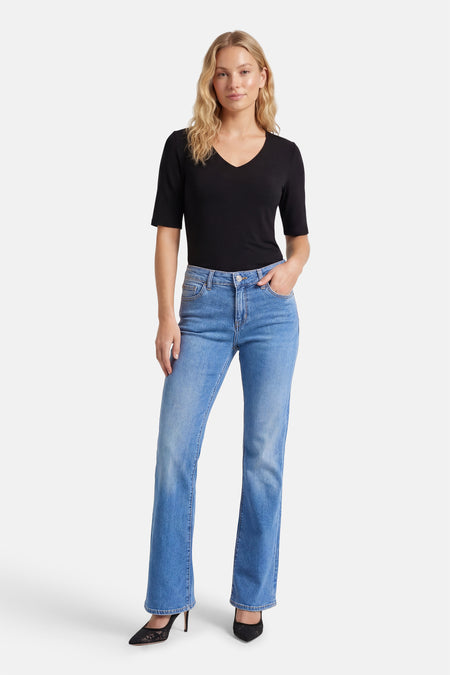 Flared jeans van lichtblauw denim by Lee Cooper, gecombineerd met een zwarte V-hals top en zwarte hakken.

