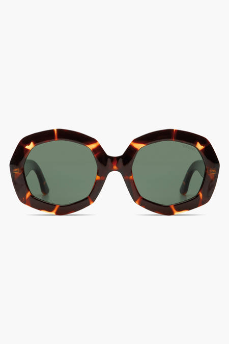 Lunettes de soleil brunes de KOMONO avec un motif de tortue mêlé et des verres verts foncés.