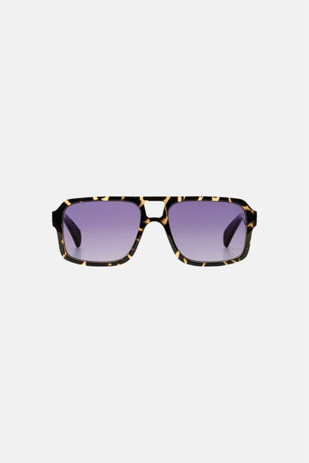 Lunettes de soleil vertes de KOMONO, avec un motif écaille de tortue et des verres violets.