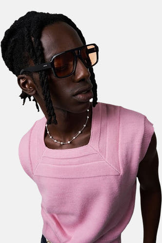 Lunettes de soleil noires KOMOMONO, portées par un modèle avec une chemise tricotée rose et une chaîne argentée.