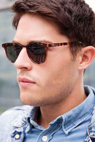 Lunettes de soleil vertes de KOMONO, portées par un homme en une chemise denim bleue, vues en profil.