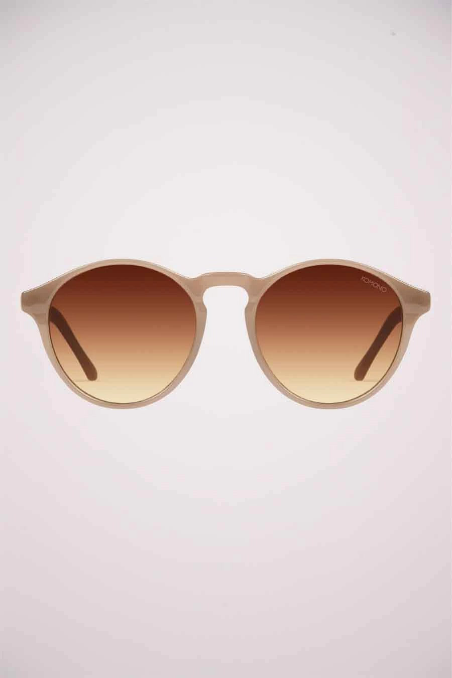 Lunettes de soleil beige de KOMONO, avec verres teintés marrons et montures arrondies.