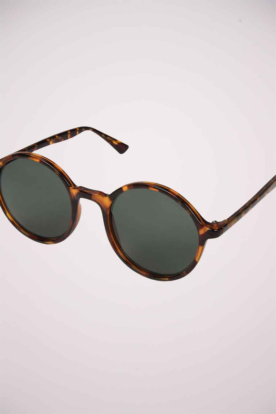 Lunettes de soleil vertes de KOMONO, avec un cadre en tortue brune.