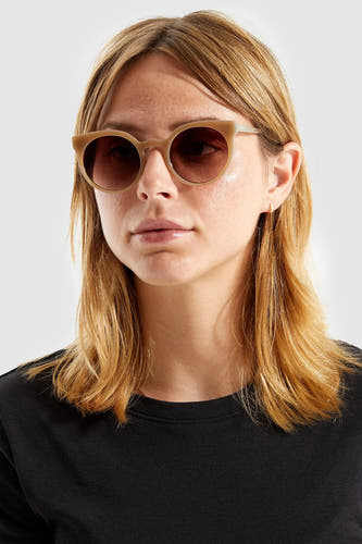 Lunettes de soleil beige de KOMONO, avec des verres ronds et un cadre de la même couleur.