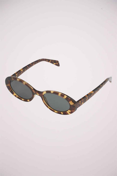 Lunettes de soleil vertes de KOMONO, avec un cadre à motif tortue et des verres ovales.