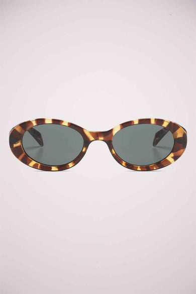 Lunettes de soleil vertes de KOMONO, avec un motif tortue et un cadre ovale.