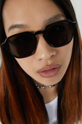 Lunettes de soleil noires de KOMONO, gros plan sur le visage d'un mannequin avec une chaîne argentée.