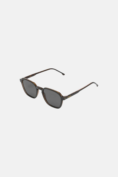 Lunettes de soleil noires KOMONO avec verres teintés et une monture géométrique écaille de tortue.