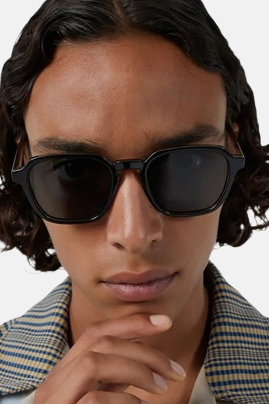 Lunettes de soleil noires et angulaires de KOMONO, portées par une personne avec une veste à carreaux, gros plan.