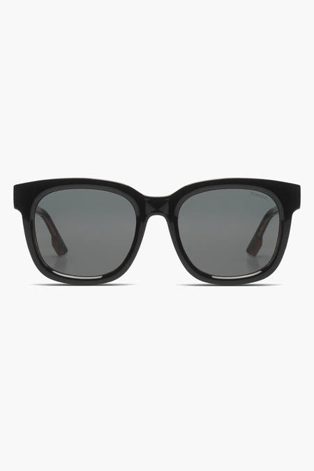 Lunettes de soleil noires KOMONO, avec un cadre brillant et des verres sombres.