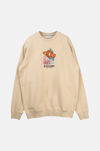 Pull écru de LAKOR, vu de dos, à manches longues et associé à un short vert et une casquette.