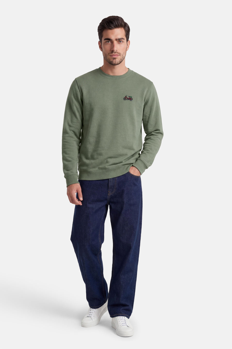 Pull vert à col rond de LAKOR, avec une petite moto brodée sur la poitrine, porté avec un jean bleu foncé et des baskets blanches.