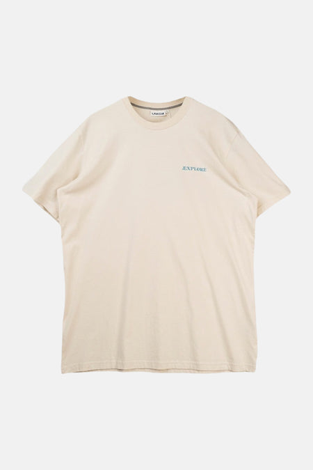 T-shirt écru de LAKOR avec un imprimé graphique d'un phoque sur une pierre pour une maison d'été.