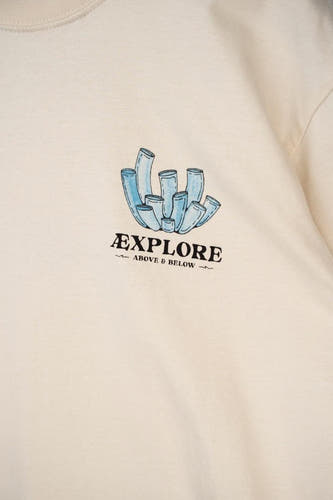 Ecru T-shirt van LAKOR met een blauwe koraalprint en de tekst "Explore Above & Below".
