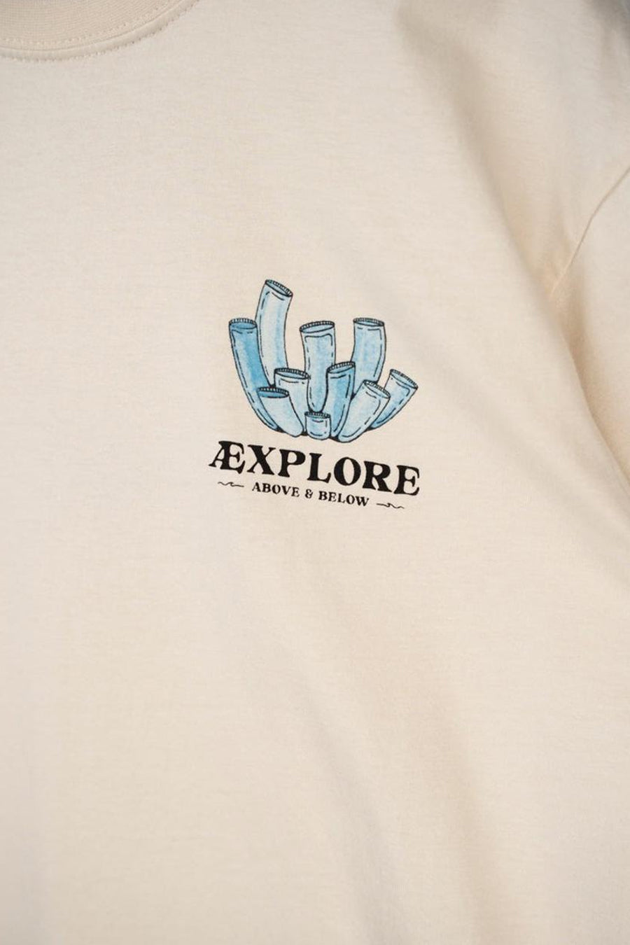 Ecru T-shirt van LAKOR met een blauwe koraalprint en de tekst "Explore Above & Below".
