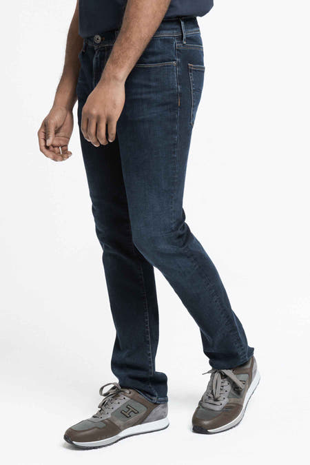 Jean bleu marine droit de Lee Cooper, avec des signes d'usure légers et des baskets grises, en vue latérale.