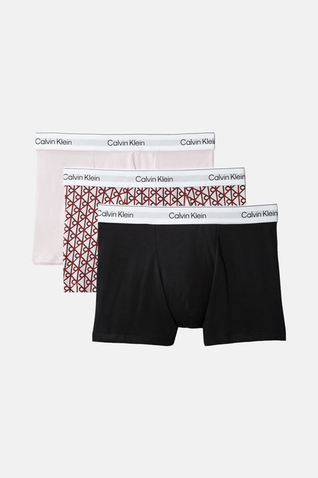 Boxershorts multicolores Calvin Klein à motif géométrique et ceinture logo blanche, portées par un homme.