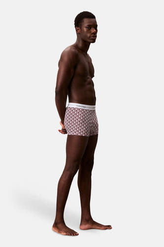 Boxer Calvin Klein à imprimé monogramme multicolore, avec ceinture blanche, porté par un homme de profil.