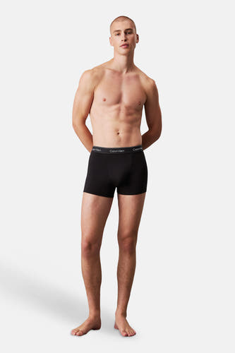 Boxer noir Calvin Klein avec ceinture à logo porté par un homme debout.
