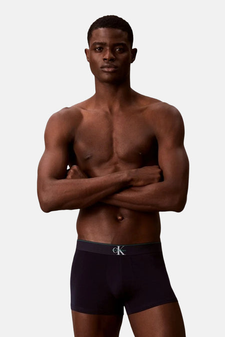 Boxer noir Calvin Klein, porté par un homme les bras croisés.