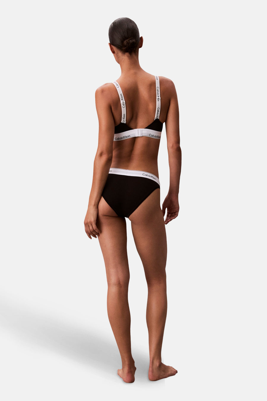 Vrouw in zwarte Calvin Klein lingerie van achteren gezien, staand.