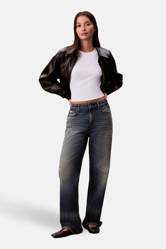 T-shirt blanc à longues manches de Calvin Klein, porté avec un manteau en cuir noir et des jeans bleus.