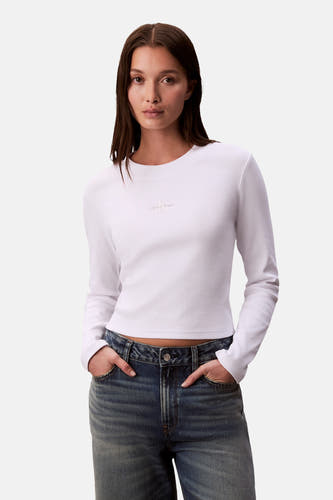 T-shirt blanc à longues manches de Calvin Klein, avec un logo subtil sur la poitrine, associé à un jean bleu.