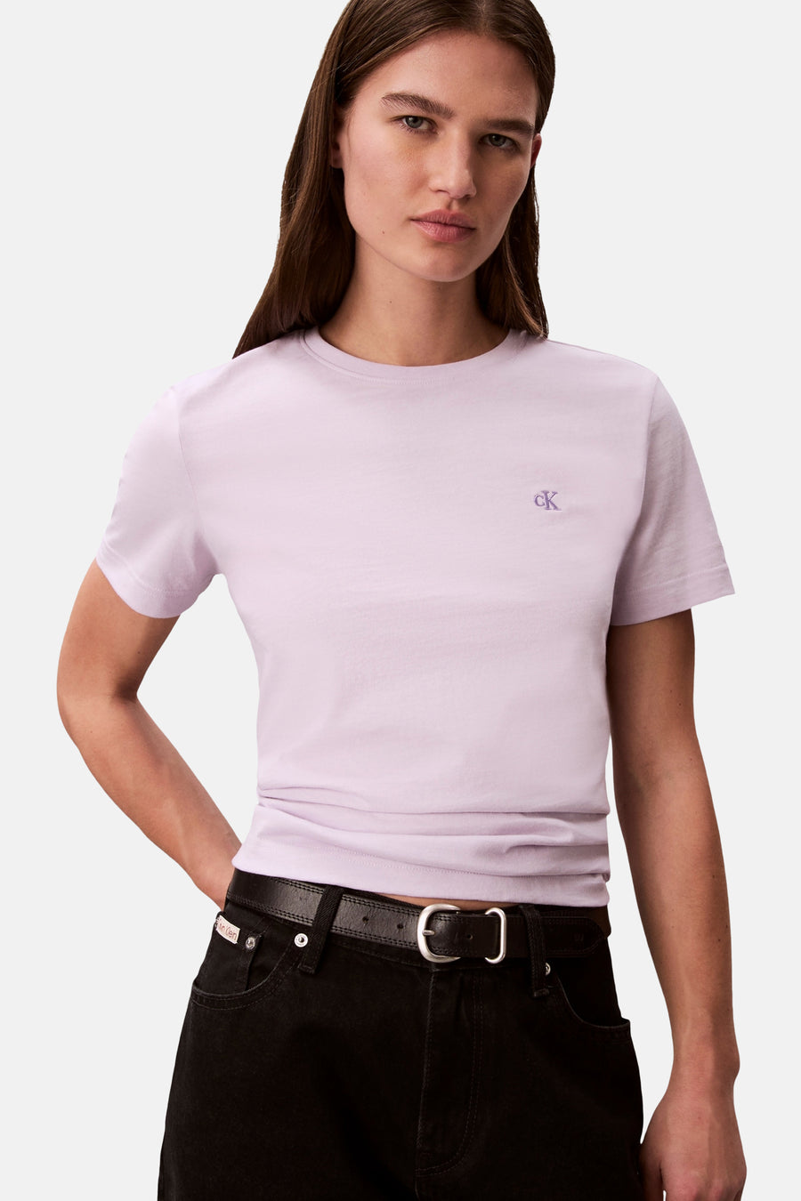 Paars T-shirt met korte mouwen van Calvin Klein, gedragen met een zwarte broek en riem.
