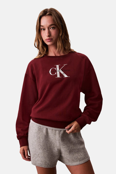 Vrouw in bordeauxrode Calvin Klein sweatshirt en grijze shorts.