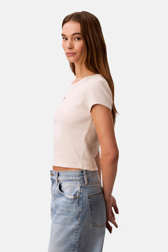 T-shirt écru à manches courtes de Calvin Klein, texture côtelée et assorti à un jean bleu.