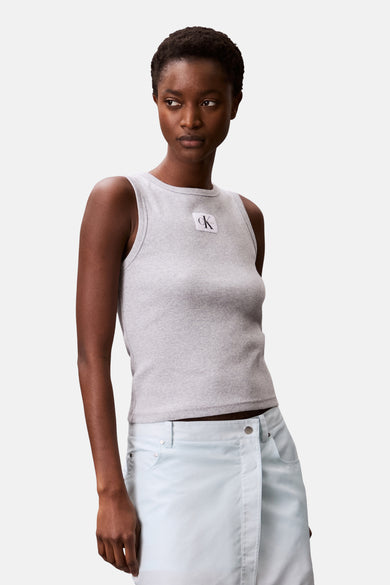 Chemise grise de Calvin Klein, avec une texture côtelée et un col rond, portée avec une jupe bleu clair.
