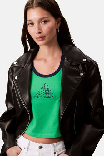 T-shirt vert avec manches courtes de Calvin Klein, imprimé d'une forme pyramidale et porté sous un blouson en cuir noir.