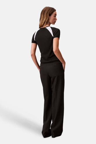 T-shirt noir à manches courtes de Calvin Klein, avec des détails blancs sur les épaules, associé à un pantalon noir.