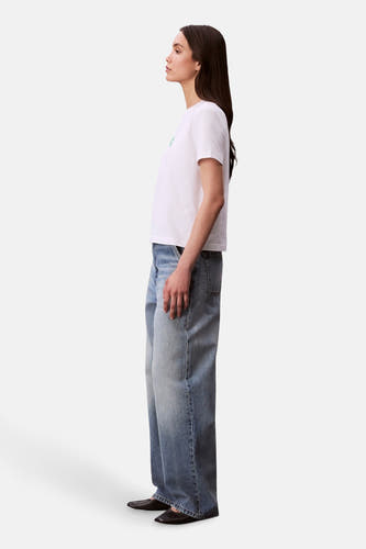 T-shirt blanc à manches courtes de Calvin Klein, avec des jeans décontractés et des chaussures noires, en vue latérale.
