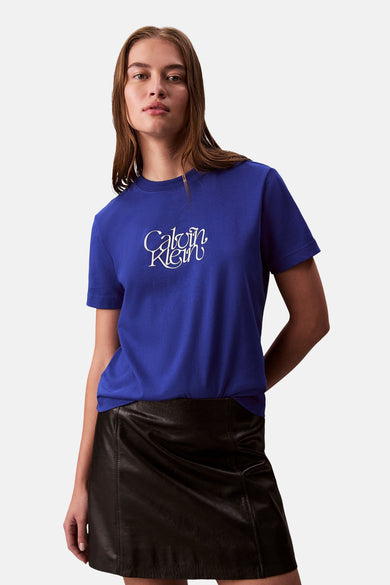 T-shirt bleu à manches courtes de Calvin Klein, porté avec une jupe en cuir noire.
