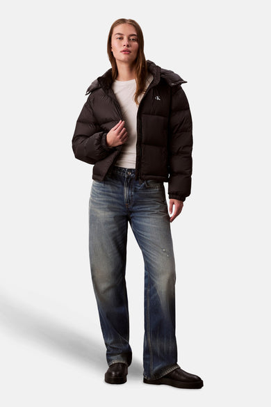 Manteau court noir de Calvin Klein, avec un haut blanc et des jeans bleus.