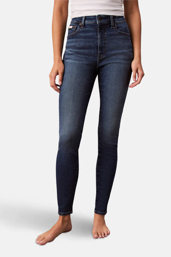 Skinny jeans in mid blue denim van Calvin Klein, gedragen met een wit topje en blote voeten.