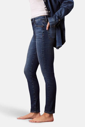 Jean skinny en denim bleu moyen de Calvin Klein, avec une main dans la poche et un t-shirt en denim décontracté.