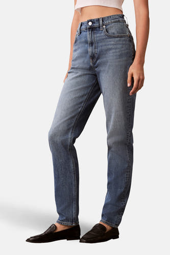 Middenblauwe mom jeans van Calvin Klein, met klassieke vijf-pocket styling en rechte pijpen, gedragen met zwarte loafers.