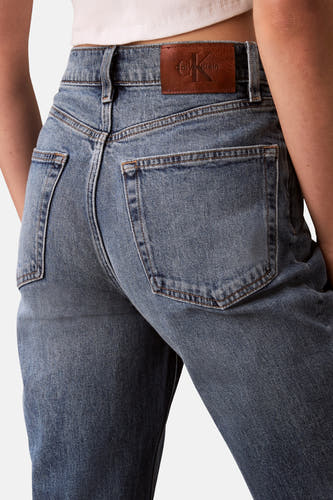 Middenblauwe mom jeans van Calvin Klein met bruin leren merklabel op de tailleband.
