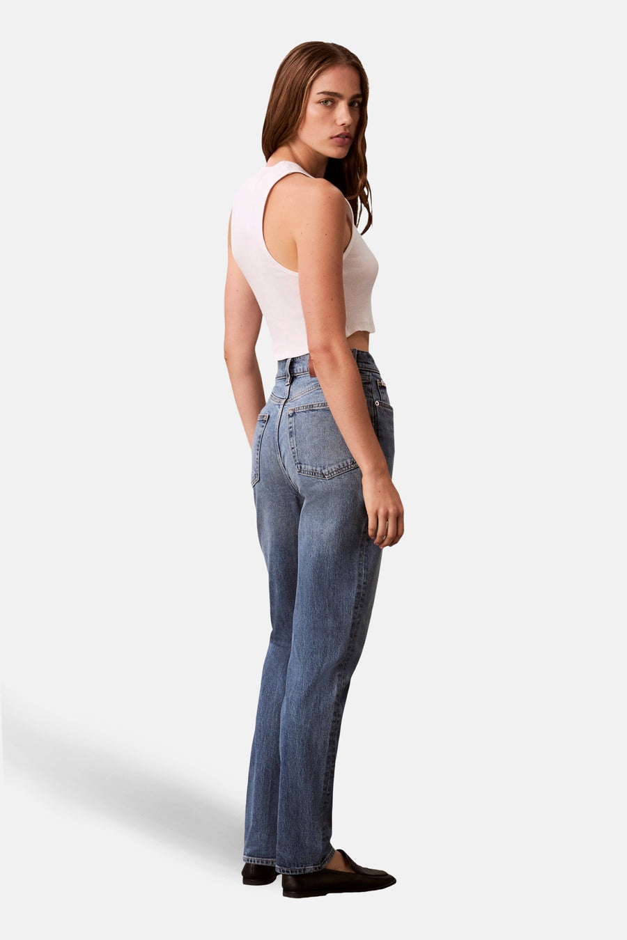 Middenblauwe mom jeans van Calvin Klein, compleet met een witte tanktop en zwarte schoenen.