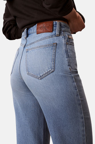 Jean coupe spéciale en denim bleu clair de Calvin Klein, avec poche arrière et étiquette de marque en cuir marron sur la ceinture.