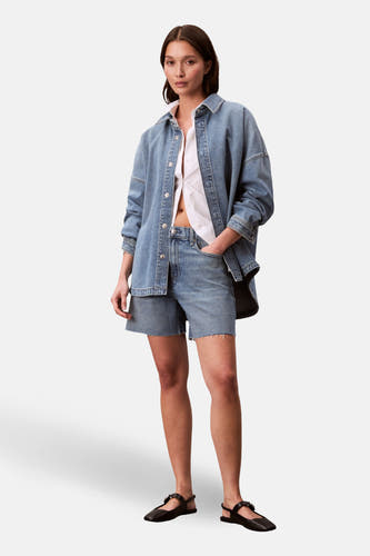 T-shirt en jeans en denim bleu Calvin Calvin Klein Calvin Calvinévert sur un t-shirt blanc et des shorts en denim.