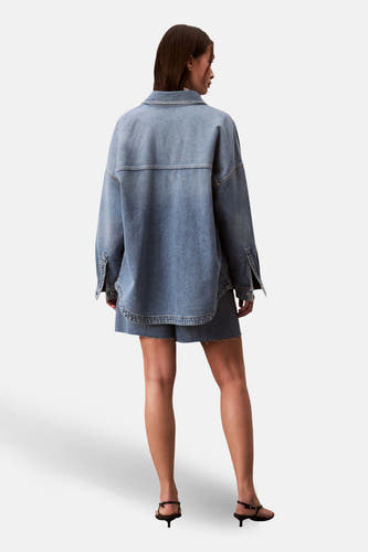 T-shirt en jeans Calvin Klein bleu denim, vu de l'arrière, porté avec des shorts coordonnés et des talons noirs.