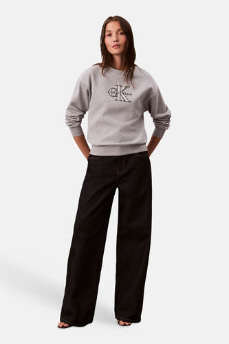 Pull-over gris de Calvin Klein, avec le logo imprimé sur l'avant, porté avec un jean foncé.