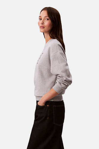 Pull gris à col rond de Calvin Klein, avec des jeans noirs.