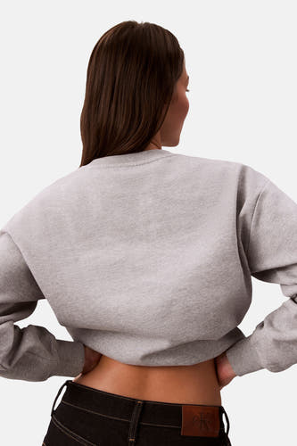 Pull-over gris avec col rond de Calvin Klein, tombant légèrement et porté avec des jeans noirs.