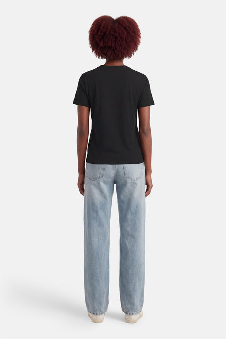 T-shirt noir Calvin Klein, vu de dos, associé à un jean bleu et des baskets blanches.