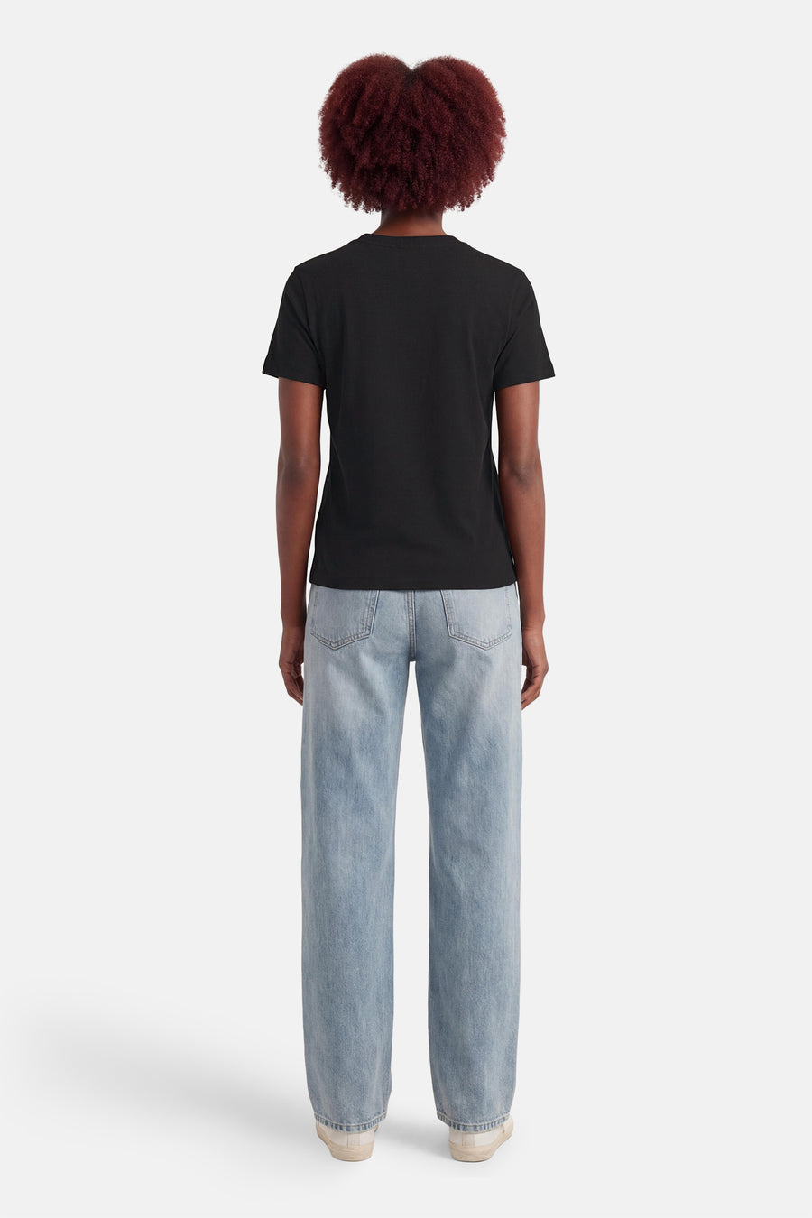 T-shirt noir Calvin Klein, vu de dos, associé à un jean bleu et des baskets blanches.