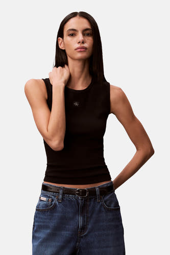 Débardeur noir Calvin Klein, avec texture côtelée et un jean avec ceinture.